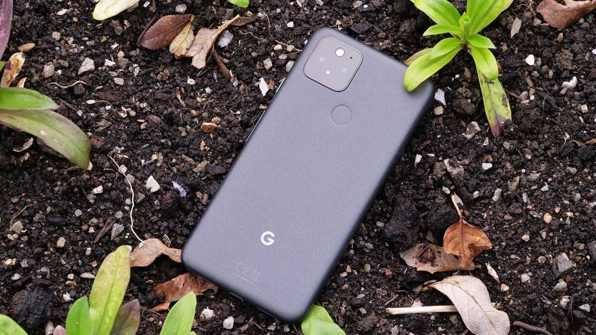 Google Pixel 5 with the back facing up sitting in a soil bed