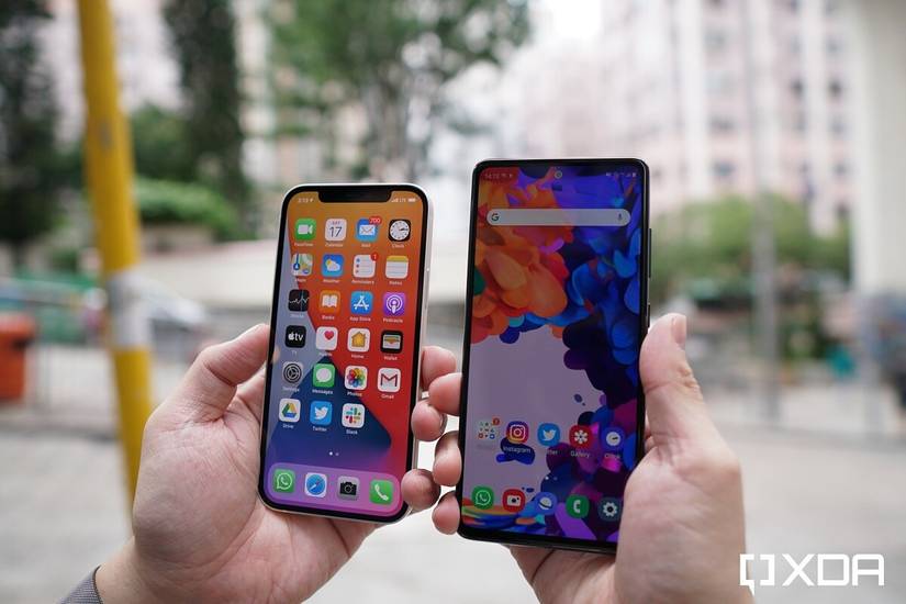 Apple iPhone 12 and Samsung Galaxy S20 FE in hand, besides each other