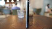 Apple iPhone 12 White and the Apple iPhone 12 Pro Pacific Blue standing upright on a table side by side