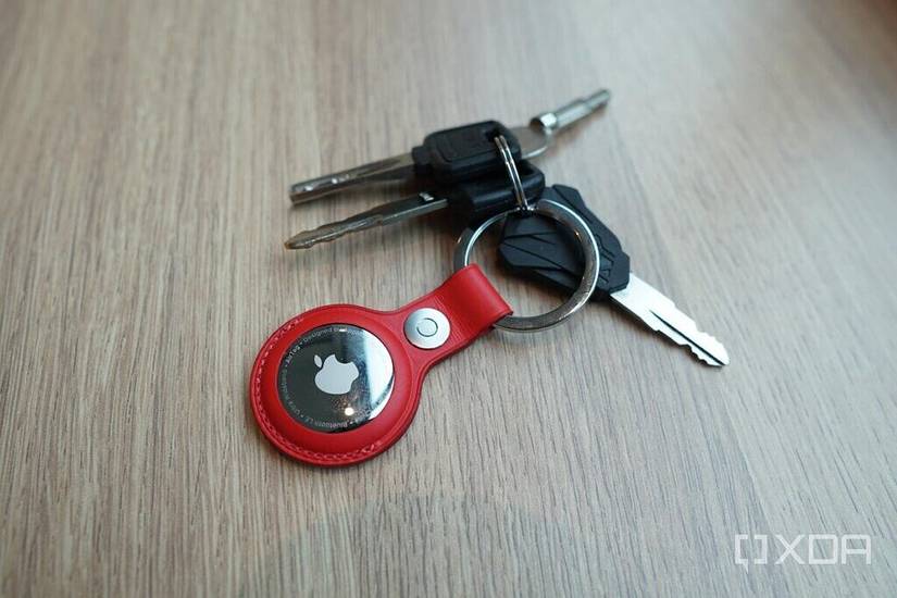 An AirTag with a red leather key ring.