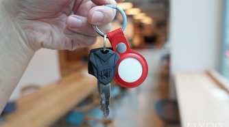 Apple's AirTags in a red leather key ring along with some keys.