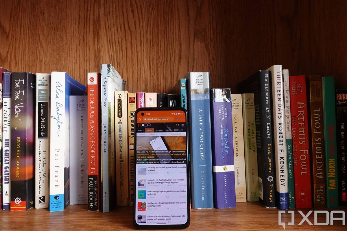 ASUS ZenFone 8 facing forwards in front of books on a bookshelf