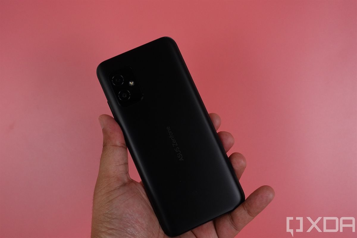 Holding up the ASUS ZenFone 8 against a pink backdrop