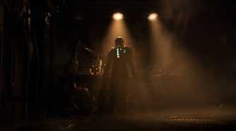 Isaac standing in a dimly lit room