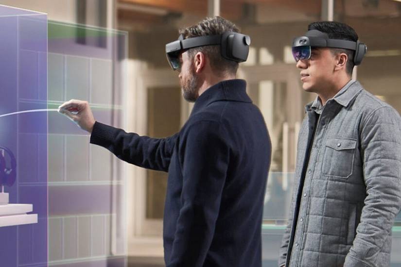 Two people wearing Microsoft HoloLens 2 heaadsets and interacting with augmented reality apps