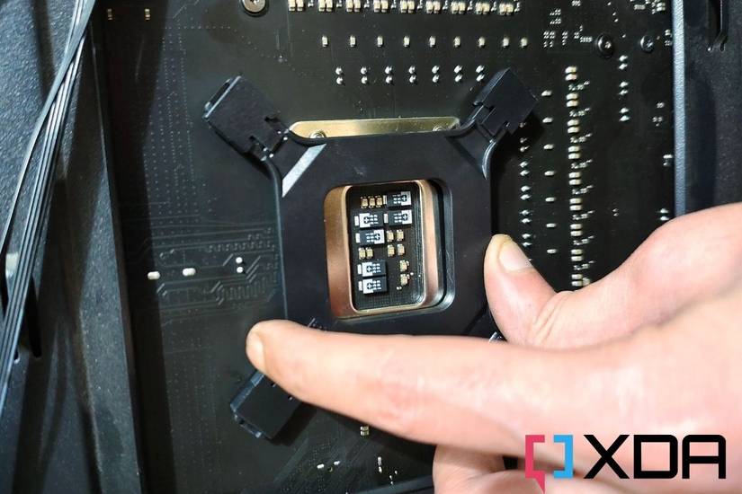 A CPU cooler backplate being installed on the back of a motherboard