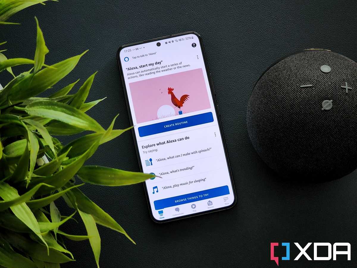 An image with the Amazon Alexa app open on a Galaxy S22 phone that's kept next to an Amazon Echo dot speaker and a green plant