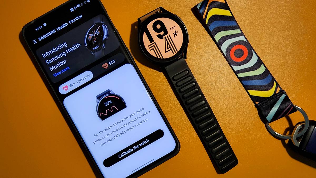 Modded Samsung Health Monitor app on OnePlus 10 Pro next to Galaxy Watch 4 on orange background