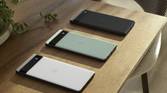 Google Pixel 6a in all three colors on wooden table.
