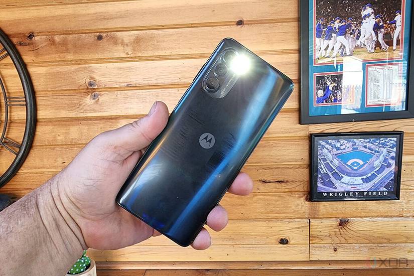 The Moto G Stylus 5G in a man's hand with the flashlight on.