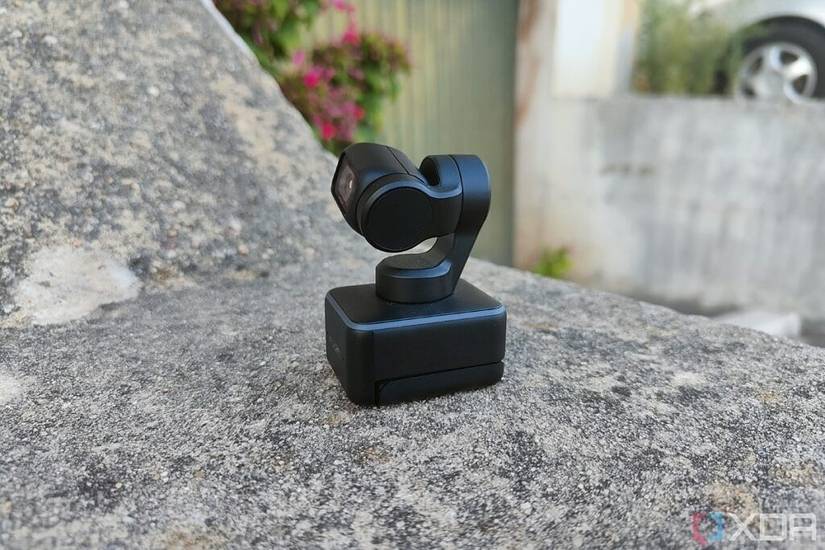 Side view of the Insta360 Link webcam sitting on a concrete wall. The monitor mount is visible from the side.