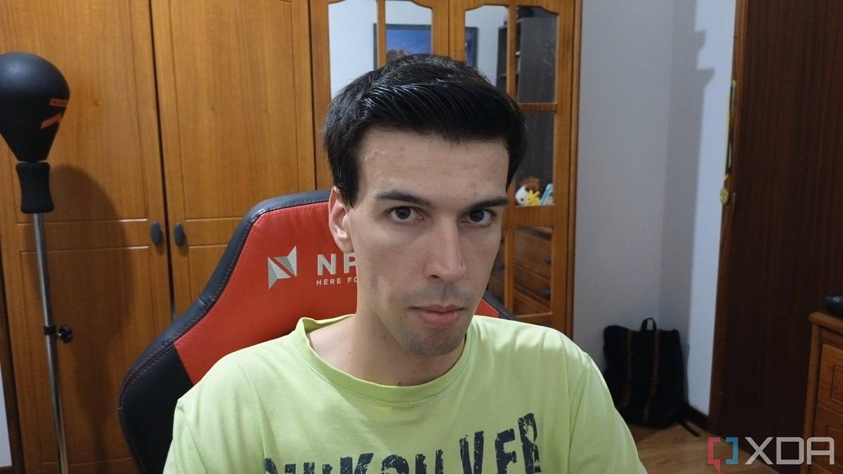 A picture of a man sitting on a chair with furniture behind him. The picture was taken with the Insta360 Link webcam with the HDR feature disabled