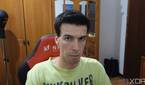 A picture of a man sitting on a chair with furniture behind him. The picture was taken with the Insta360 Link webcam with the HDR feature disabled
