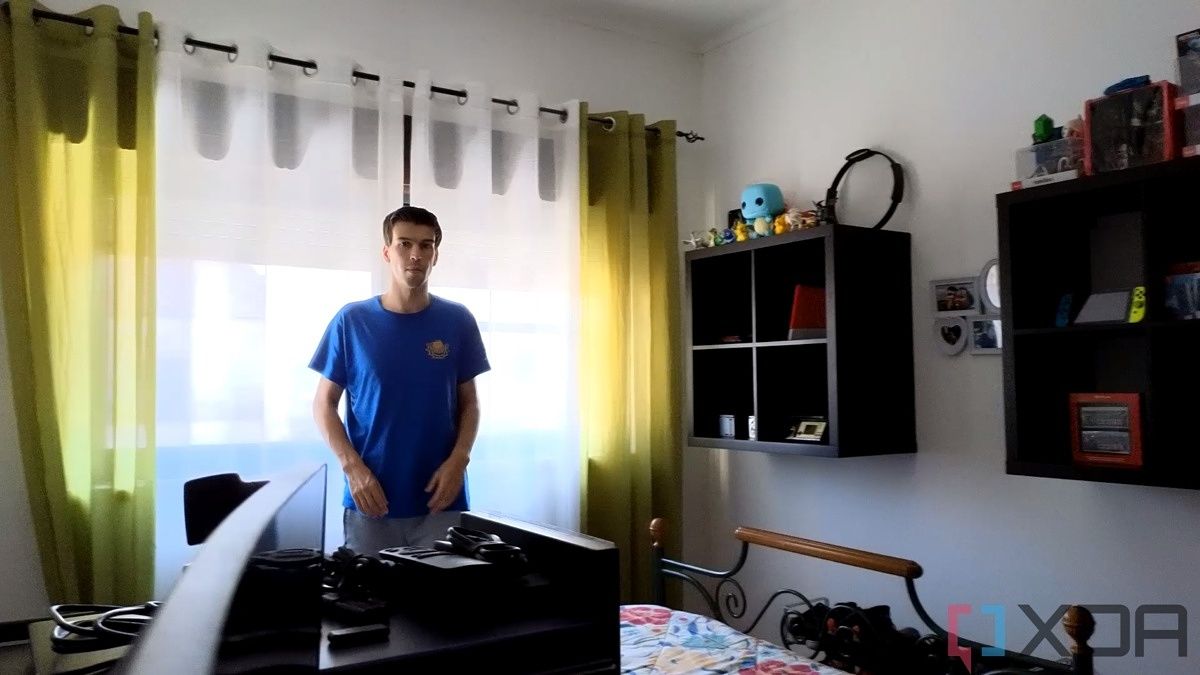 A picture of a man standing in front of a window with strong sunlight outside. Some shapes can be seen outside the window. The image is a sample taken from a video recorded with the Insta360 Link webcam