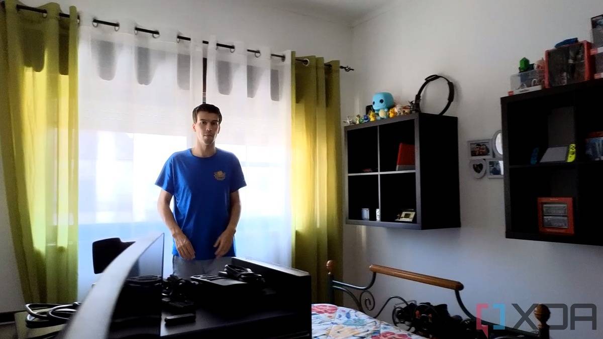 A picture of a man standing in front of a window with strong sunlight outside. Some shapes can be seen outside the window. The image is a sample taken from a video recorded with the Insta360 Link webcam