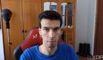 A picture of a man sitting on a chair with a wardrobe in the background. The picture was taken with the Insta360 Link webcam