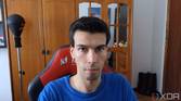 A picture of a man sitting on a chair with a wardrobe in the background. The picture was taken with the Insta360 Link webcam