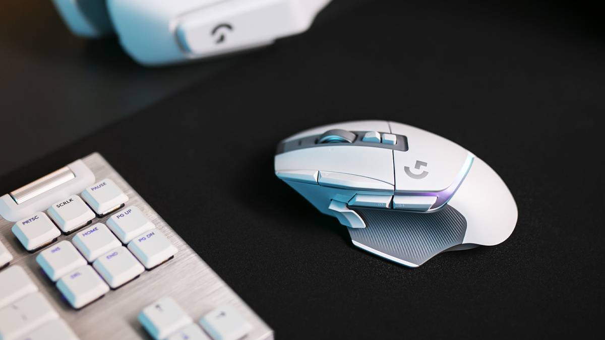 Logitech G502 X Plus next to a keyboard on a blakc mat