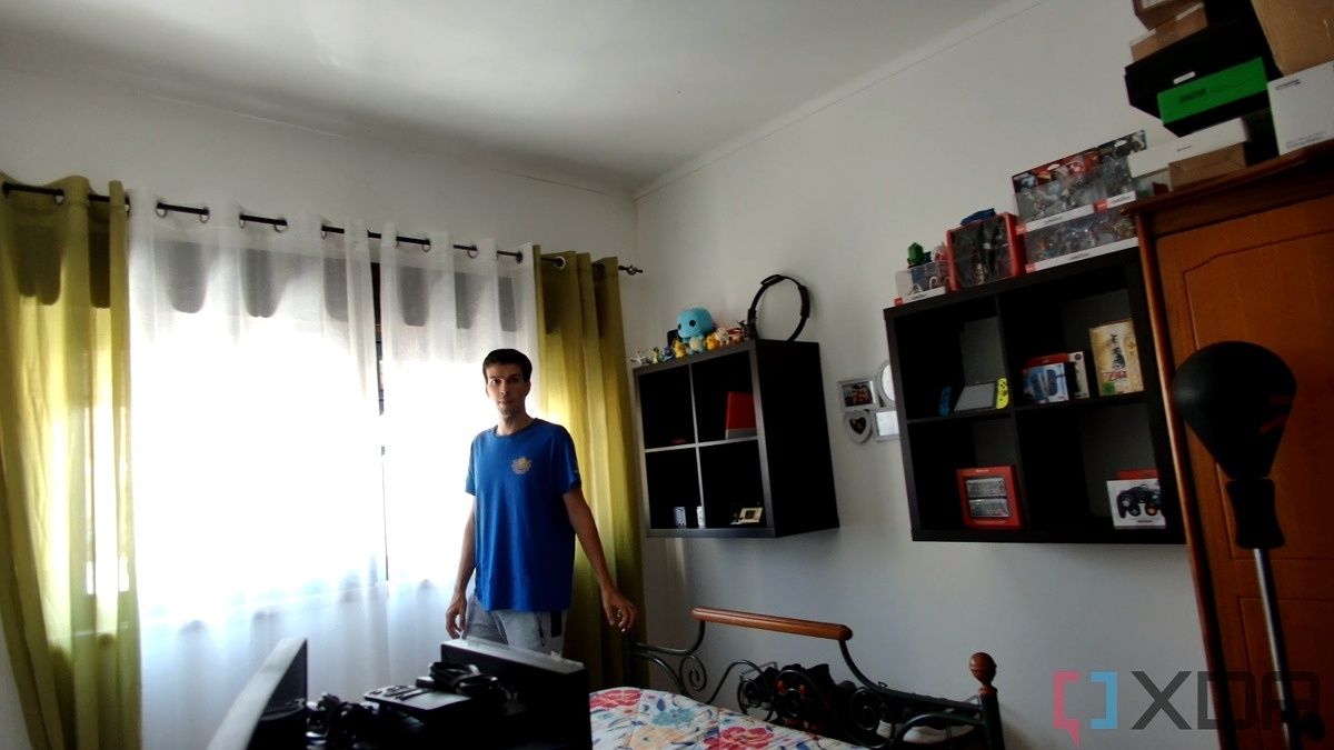 A picture of a man standing in front of a window with strong sunight outside. Nothing is discernible outside the window due to the strong light. The picture is a sample taken from a video recorded with the Obsbot Tiny 4K webcam