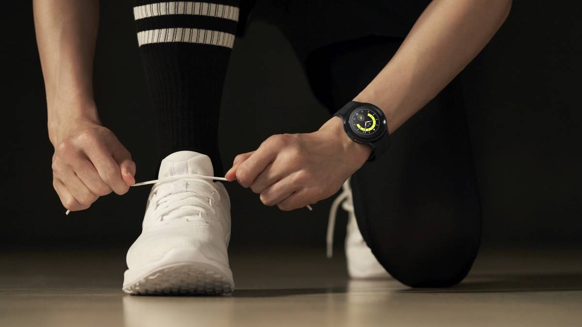 A person wearing the Galaxy Watch 5 on their wrist lacing their shoes.