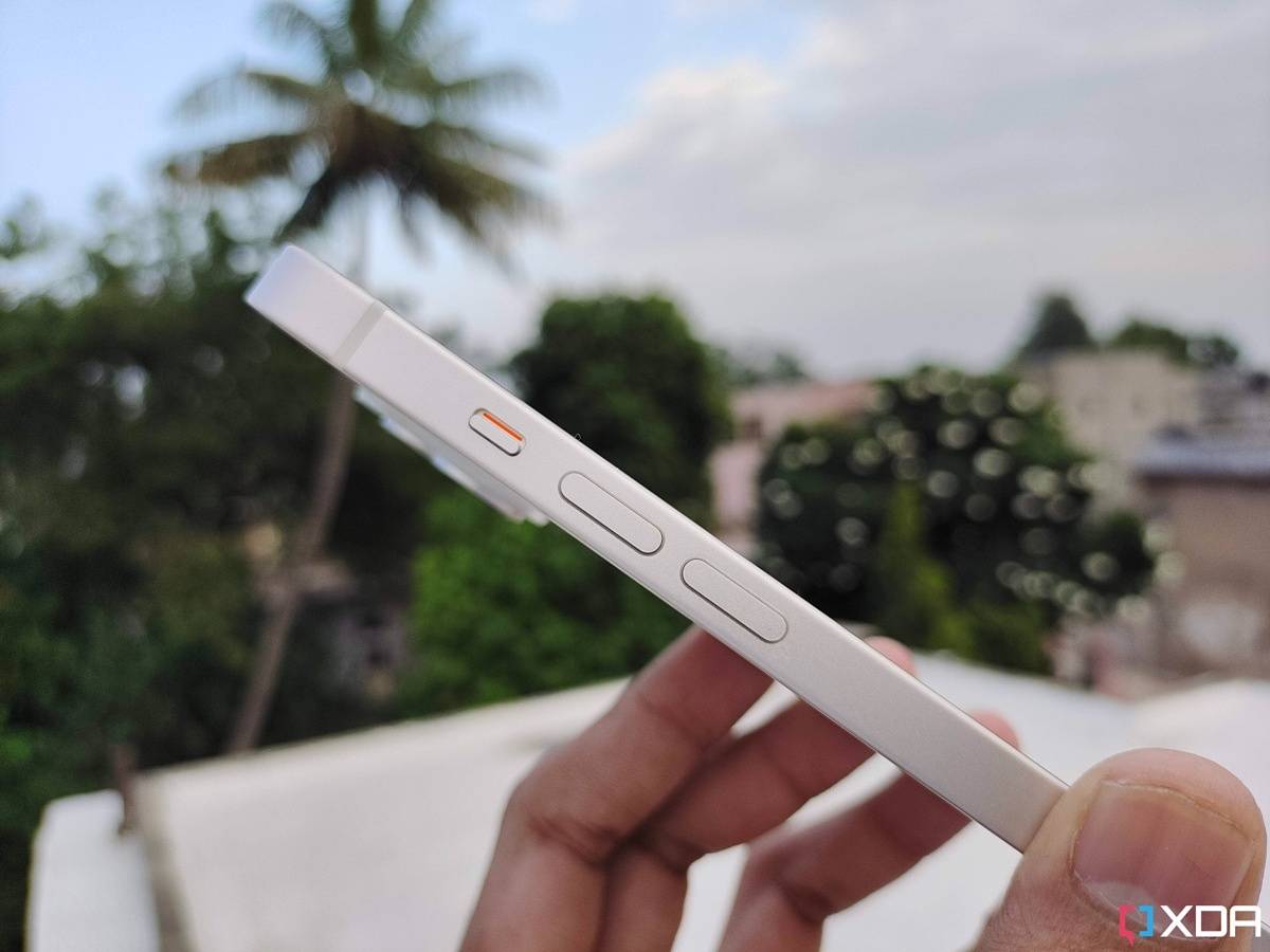 iPhone 14 held. in hand with the mute switch and volume buttons vislble