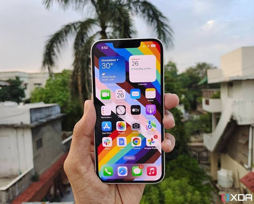 iPhone 14 held in hand against the backdrop of a palm tree