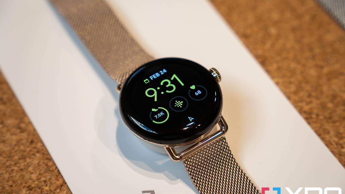Google Pixel Watch on white surface with gold metal mesh band.