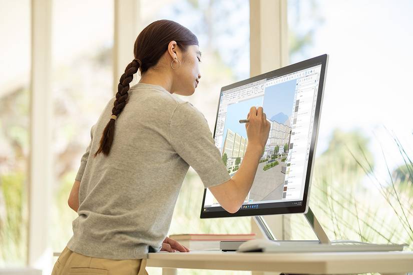 A woman using the Surface Pen on a Surface Studio 2 Plus on a desk