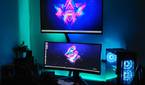 An image showing a gaming setup with a TV, monitor, and a gaming PC case on a desk with some RGB lights.