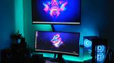 An image showing a gaming setup with a TV, monitor, and a gaming PC case on a desk with some RGB lights.