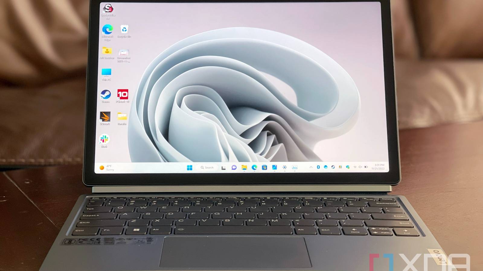 The Lenovo IdeaPad Duet 5i sitting on a table with a sofa in the background.
