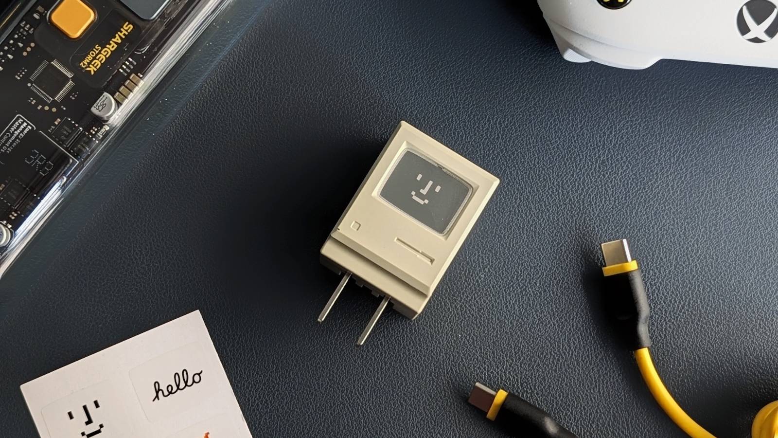 An image of the Shargeek Retro 35W charger in the middle with a bunch of other miscellaneous products around it on a leather desk mat.