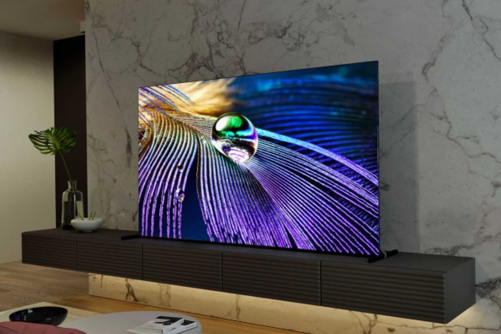 An image of the Sony Bravia XR A90J OLED TV kept on a wooden cabinet with marble finished-wall in the background.