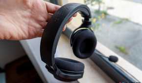 A Razer Barracuda X headset held on a person's hand by the headband, with a window in the background