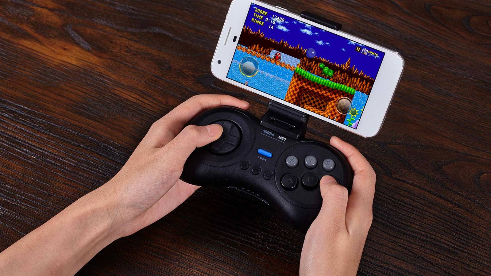 An image showing a person using the 8Bitdo M30 retro controller to play games on a smartophone.