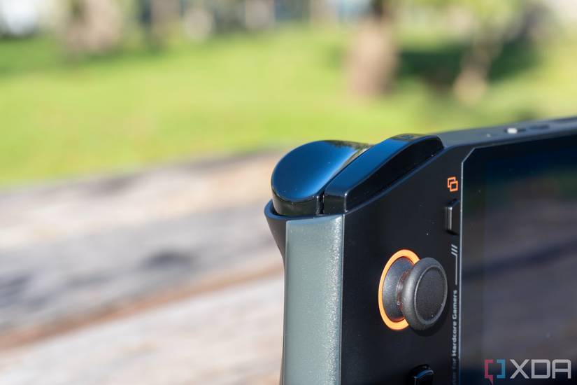 Close-up view of the shoulder button and trigger on the left side of the One Xplayer Mini Pro. The analog stick on the front is also visible