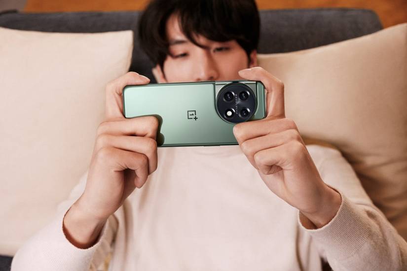 Person wearing a pink sweatshirt holding a green OnePlus 11.