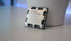 AMD Ryzen 9 7900 processor resting against a white container on a white desk