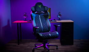 A gaming chair with a Razer-branded headrest mounted on it. The headrest has speakers on both sides.