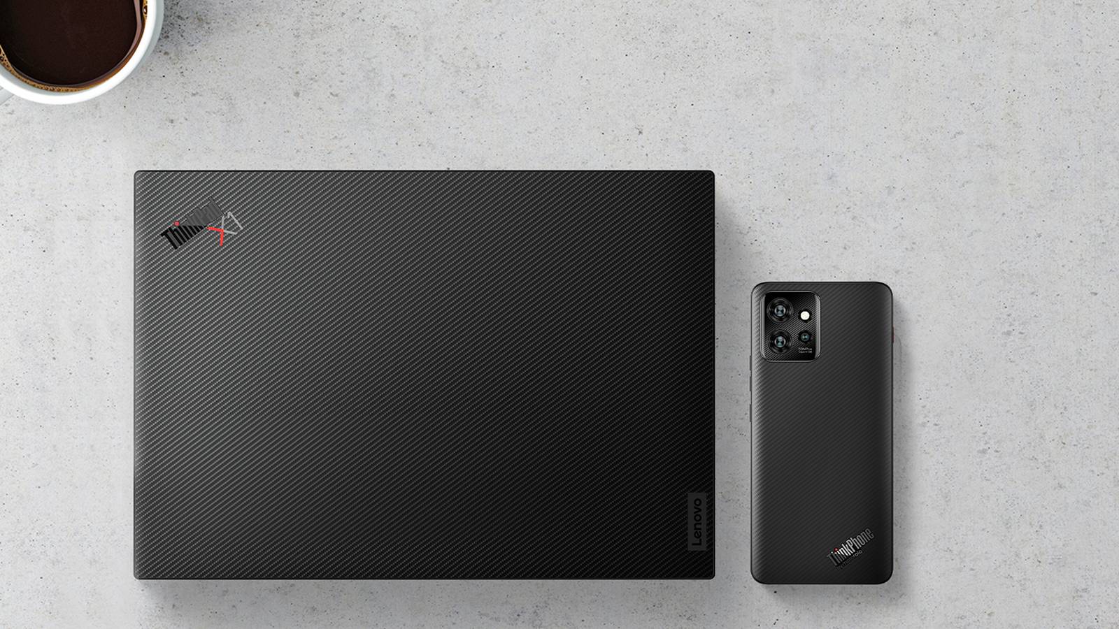 Lenovo ThinkPhone by Motorola next to a ThinkPad on a granite countertop.