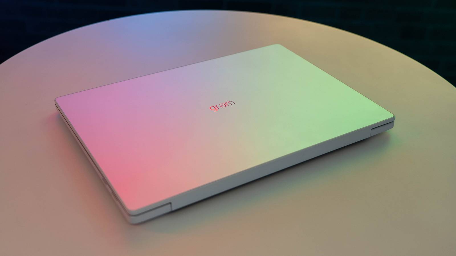 Iridescent laptop with gram branding on white table