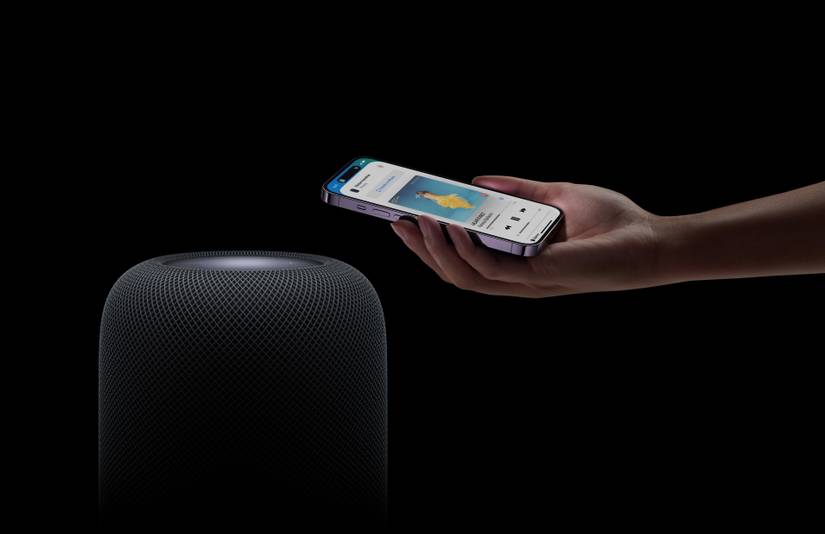Person holding an iPhone next to the HomePod 2.