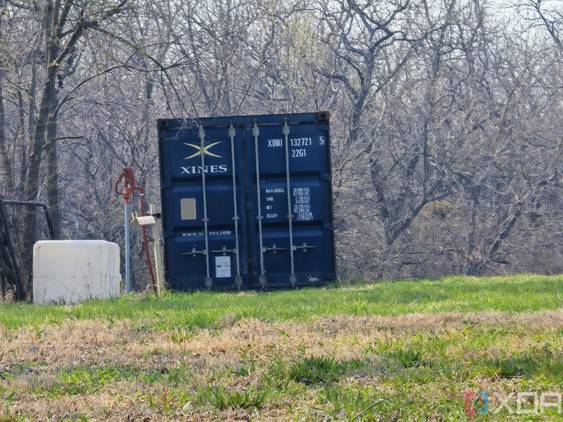 Outdoor photo of a barn and shipping container at 10x zoom
