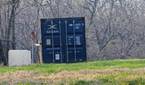 Outdoor photo of a barn and shipping container at 10x zoom