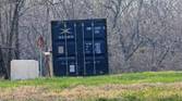 Outdoor photo of a barn and shipping container at 10x zoom
