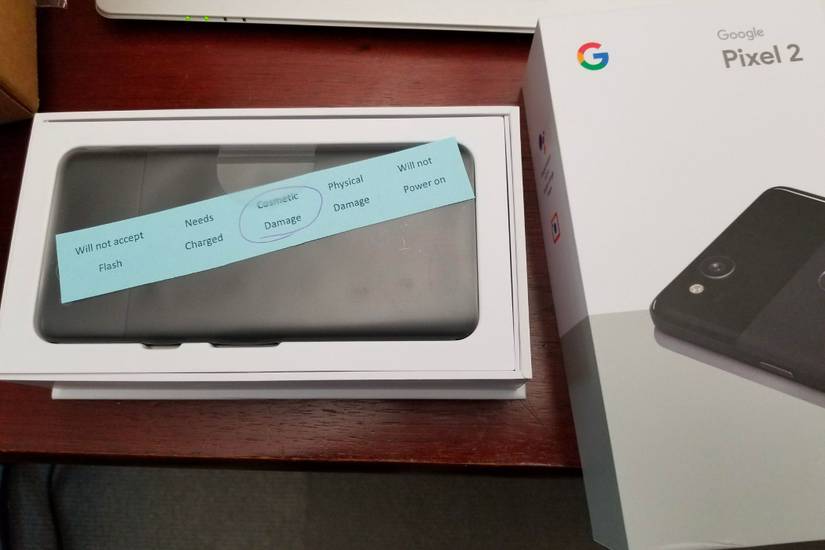 An image showing a Pixel 2 in its retail box with a QC fail sticker that highlights cosmetic damage.