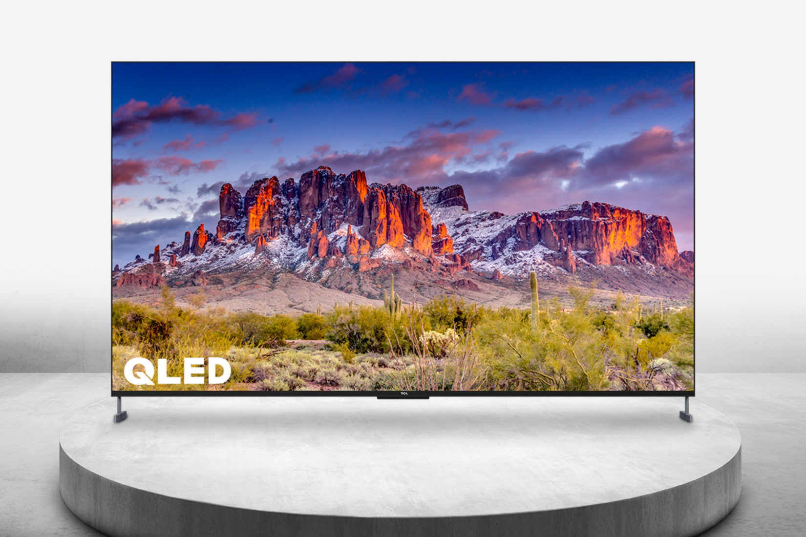 tcl 98-inch QLED TV on a marble pedestal with majestic mountain scene being shown on display