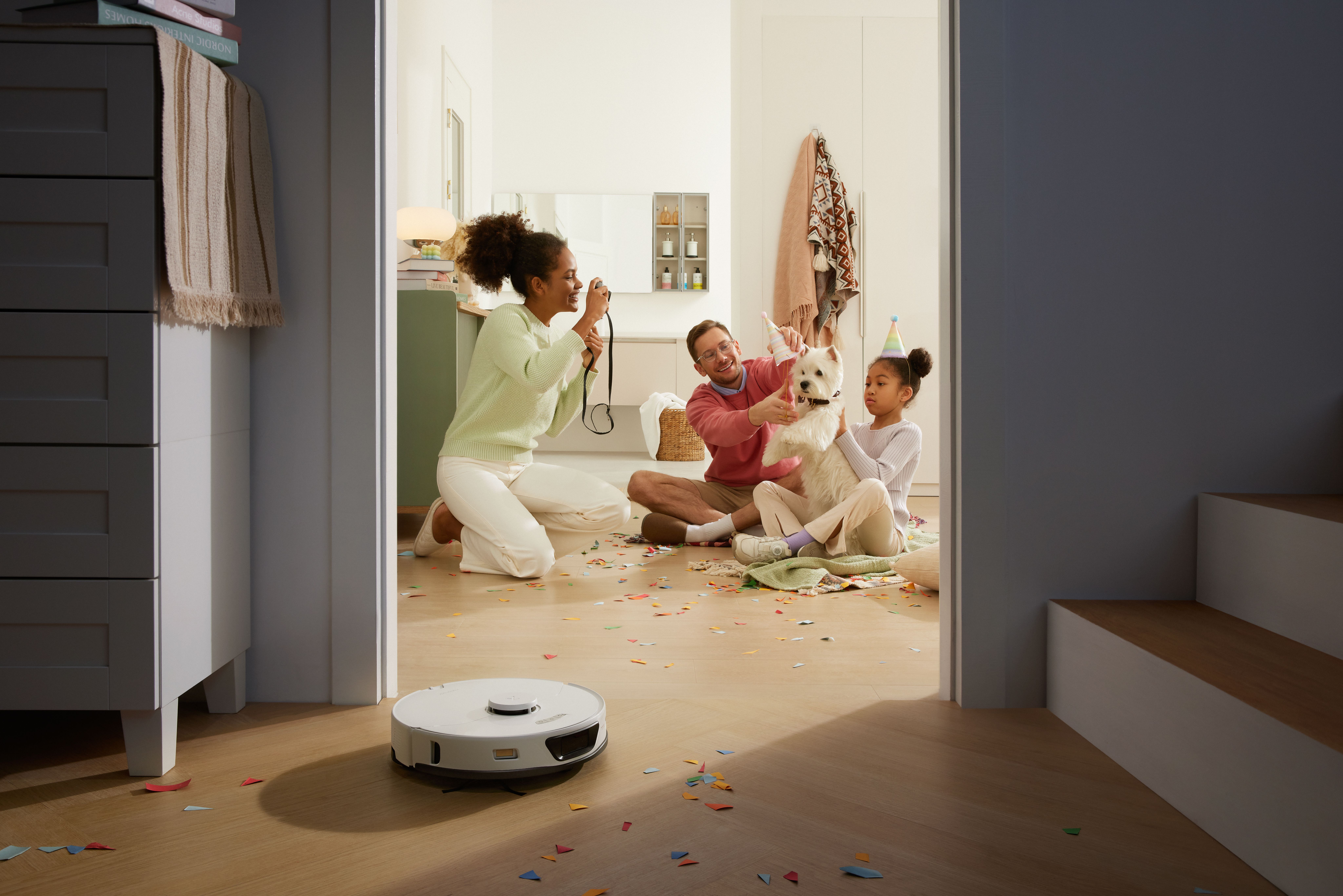 Roborock S7 Max Ultra cleaning up confetti with family in background.
