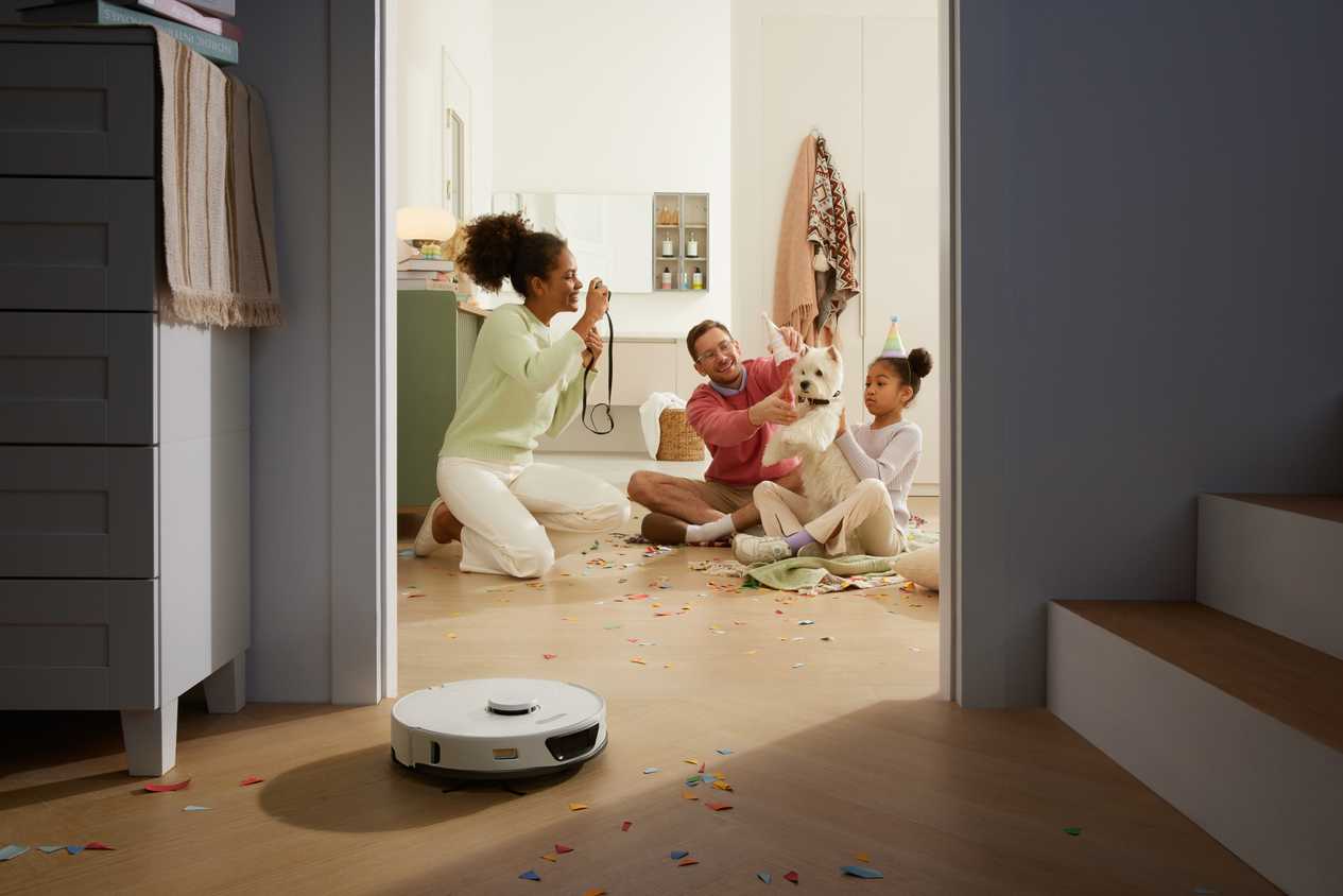 Roborock S7 Max Ultra cleaning up confetti with family in background.