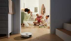 Roborock S7 Max Ultra cleaning up confetti with family in background.